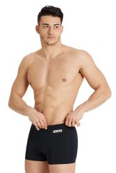 Badbyxor Team Solid Short, Svart, 30 Badbyxor i svart med logotyp, används av en manlig modell som justerar byxorna. Modellen står med överkroppen bar.