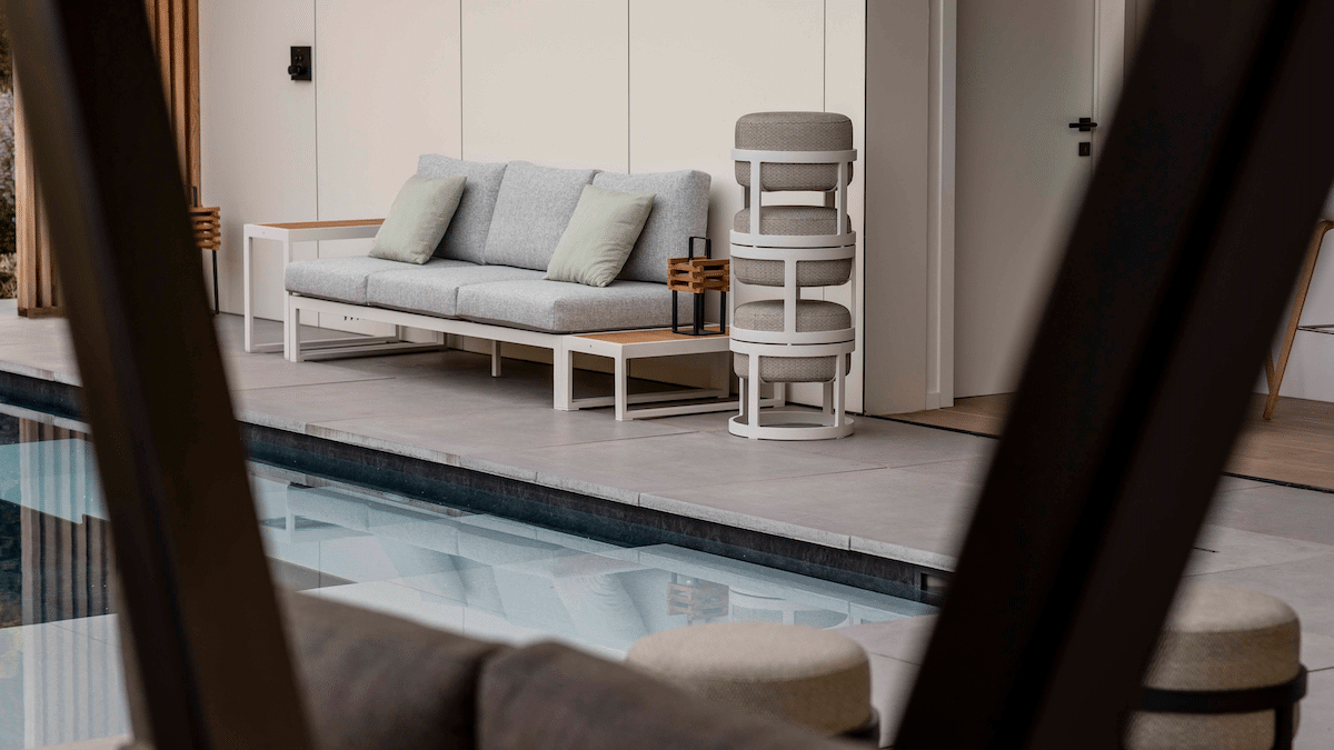 Några compact pallar är staplade bredvid en soffa vid en pool