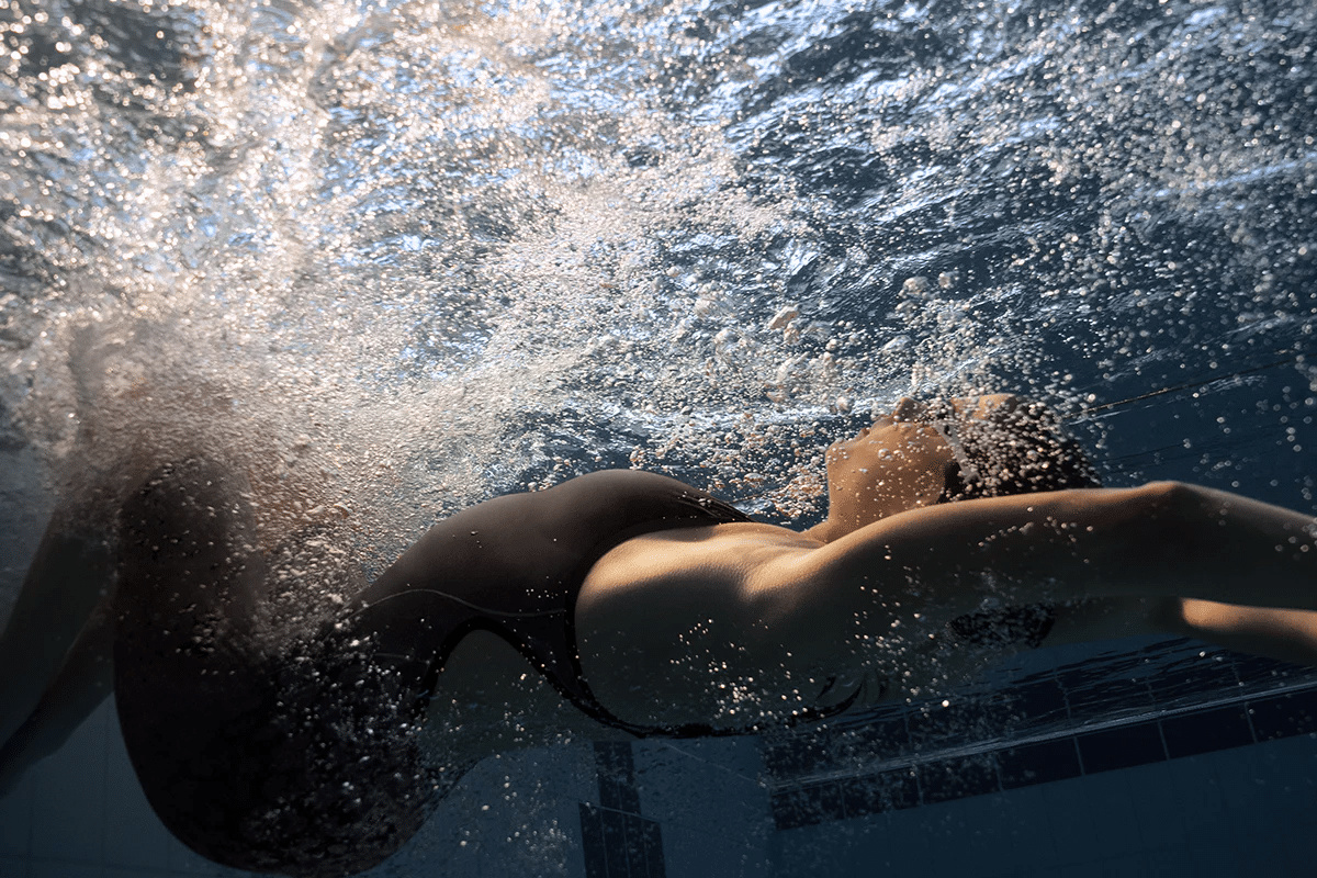En dam i Impulso tävlingsbaddräkten simmar under vatten