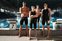 Fyra personer i Impulso tävlingsdräkter står framför en pool