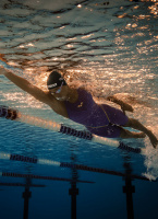 En dam i baddräkten simmar under vatten