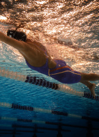 En dam i baddräkten simmar under vatten