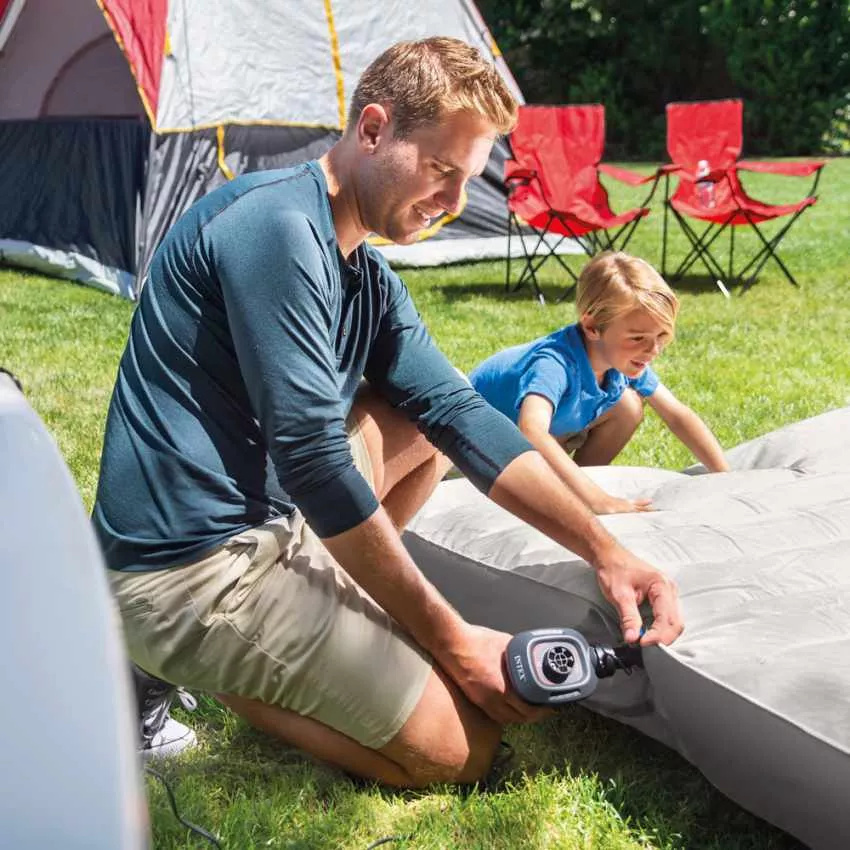 En man och en pojke blåser upp en madrass med pumpen