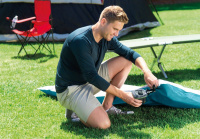 Quickfill Batteridriven Luftpump En man blåser upp en madrass med pumpen på en gräsmatta