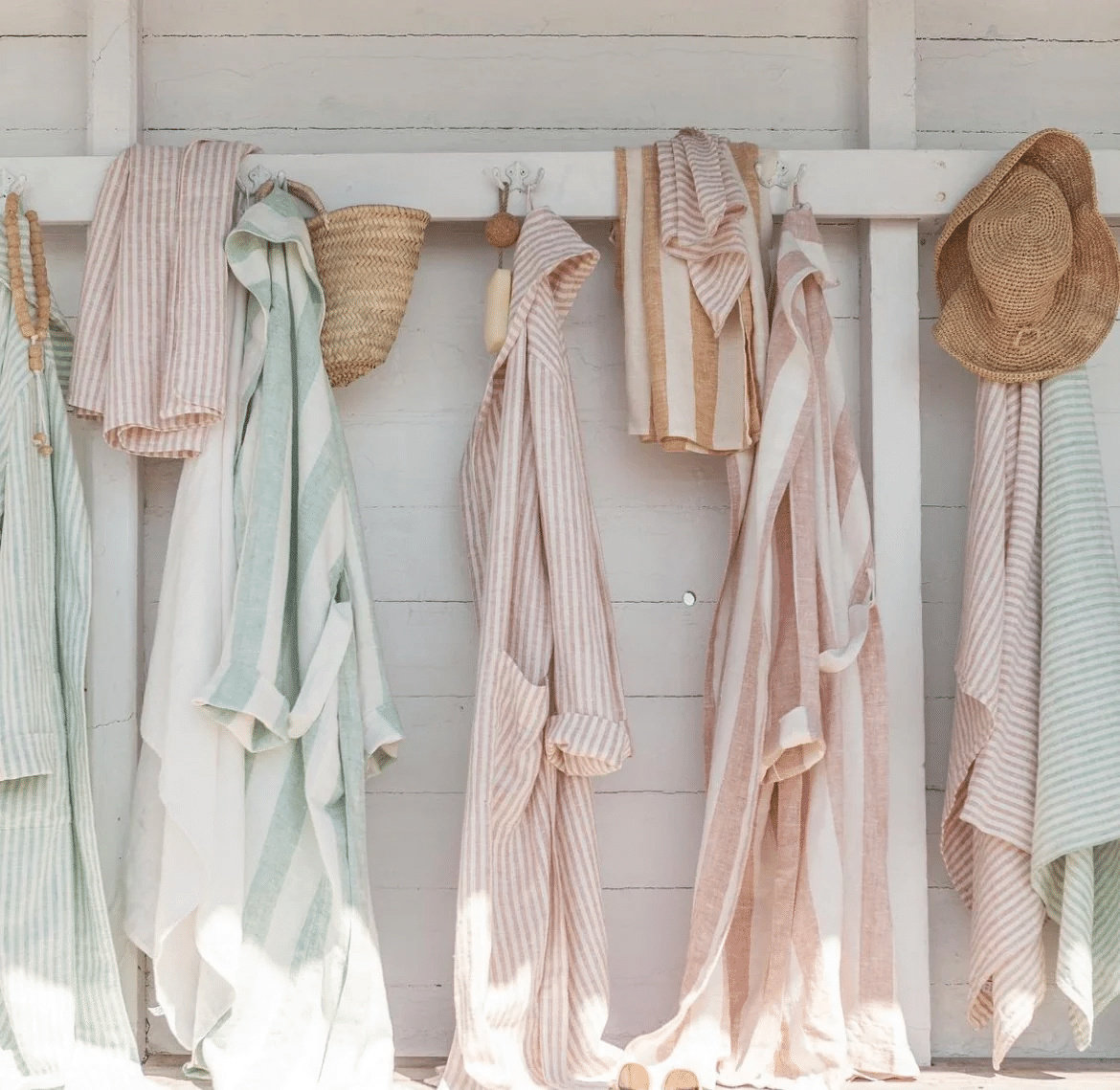 Flera morgonrockar och handdukar hängande på en vit vägg