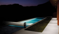 En nattbild på en upplyst pool med ett upprullat Tixit skydd vars stativ lyser