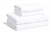 Fyra vita handdukar och badlakan staplade ovanpå varandra mot en vit bakgrund.