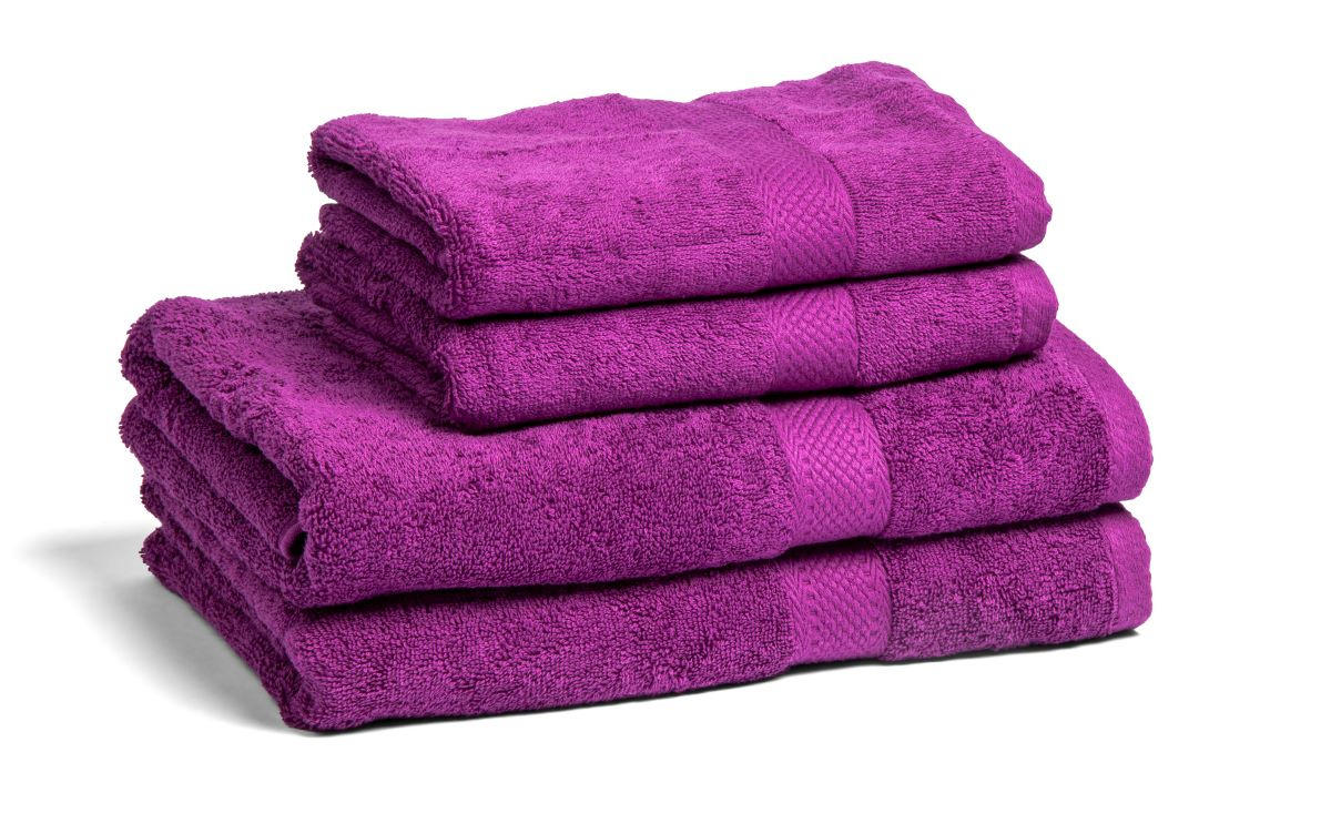 Fyra lila handdukar och badlakan staplade ovanpå varandra mot en vit bakgrund.