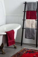 Röda, grå, och sandfärgade badlakan hängande över och bredvid ett badkar.