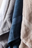 Närbild på handdukarna i vitt, grått, denim, och sand.
