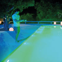 LumiPlus Flexi Plug & Play RGB, 2-pack En man står med fjärrkontrollen vid en pool på natten