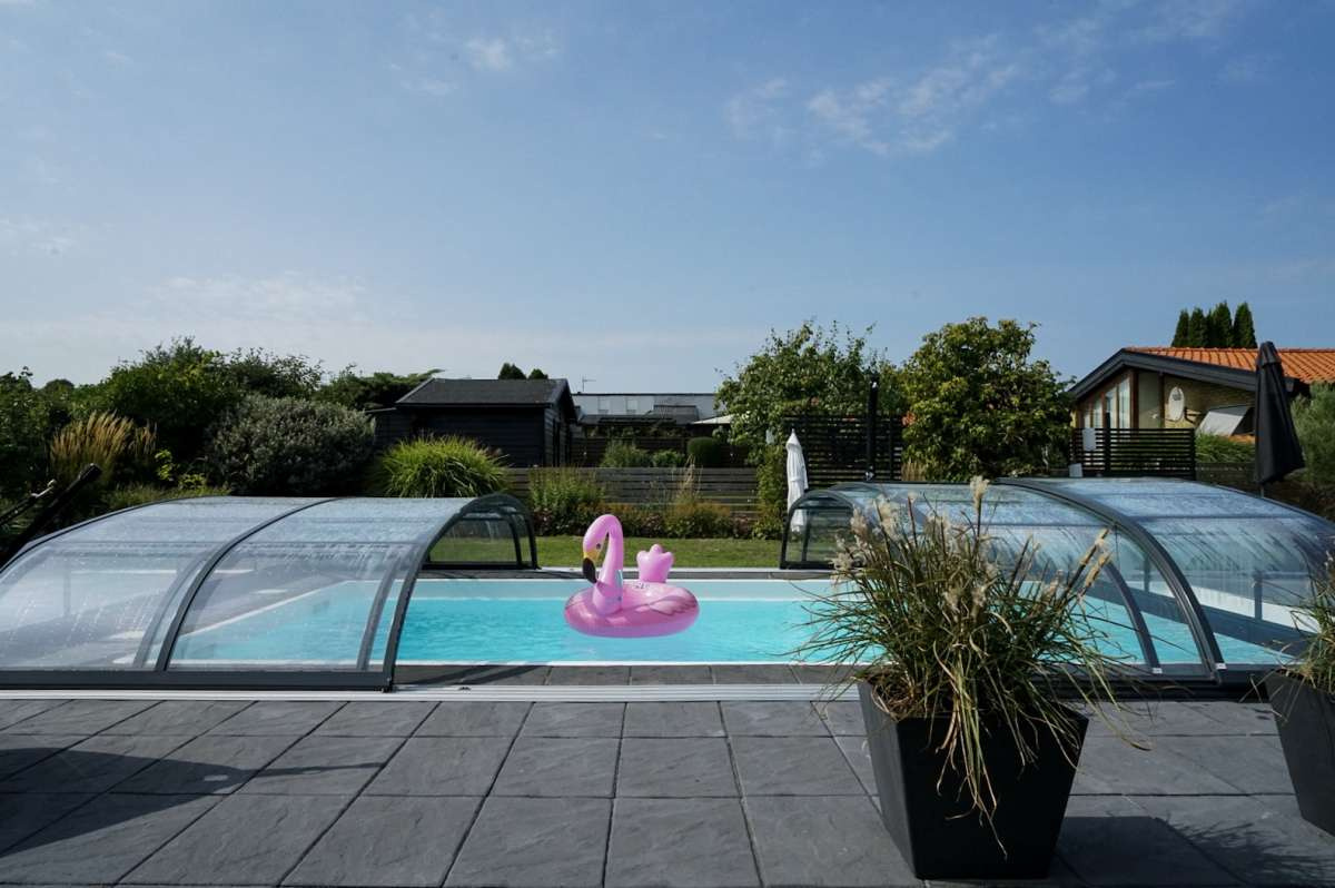 Pooltaket öppnat på mitten med en uppblåsbar flamingo i poolen
