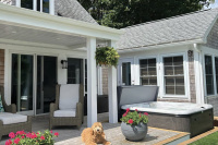 Spabad Signature Self-Cleaning 455 - Gold Spabadet med ett öppet lock utomhus bredvid en altan framför ett hus.