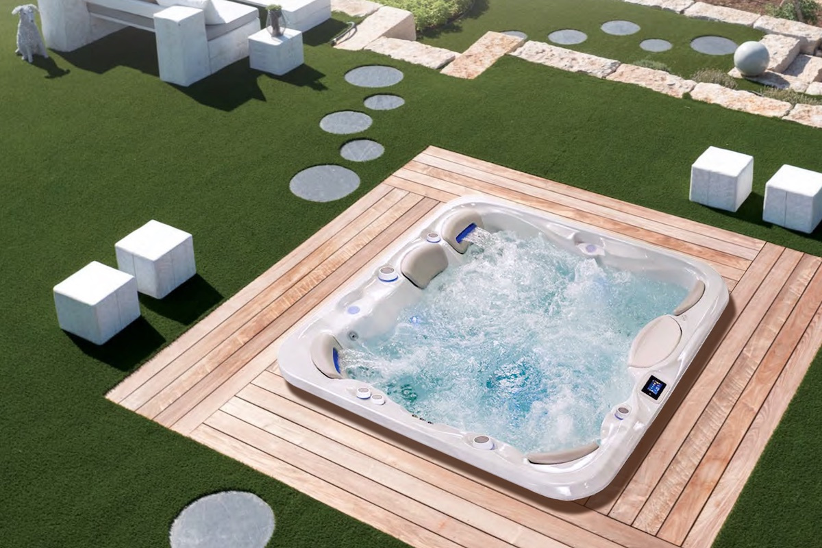 Spabadet nedsänkt i en gräsmatta med trall och stenar runtomkring