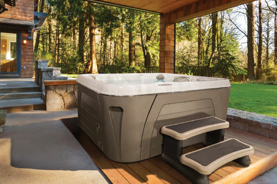 Spabadet på en uteplats bredvid ett hus, skog och en gräsmatta