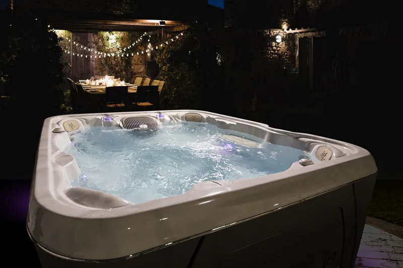 Spabadet utomhus på natten med ett dukat bord bakom