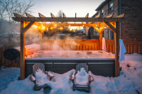 Spabadet med ett rullock Ett öppet swimspa i skymningen omgiven av snö