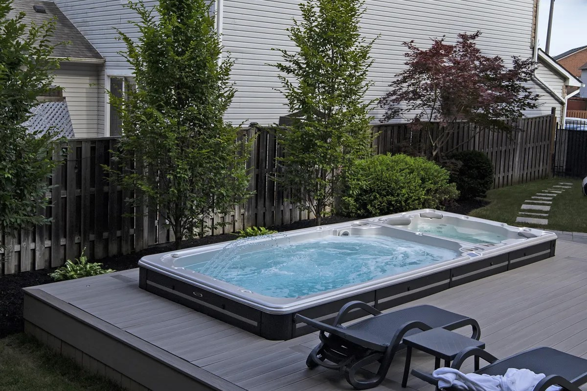 Swimspabadet på dagen på en uteplats med ett staket och växter i bakgrunden