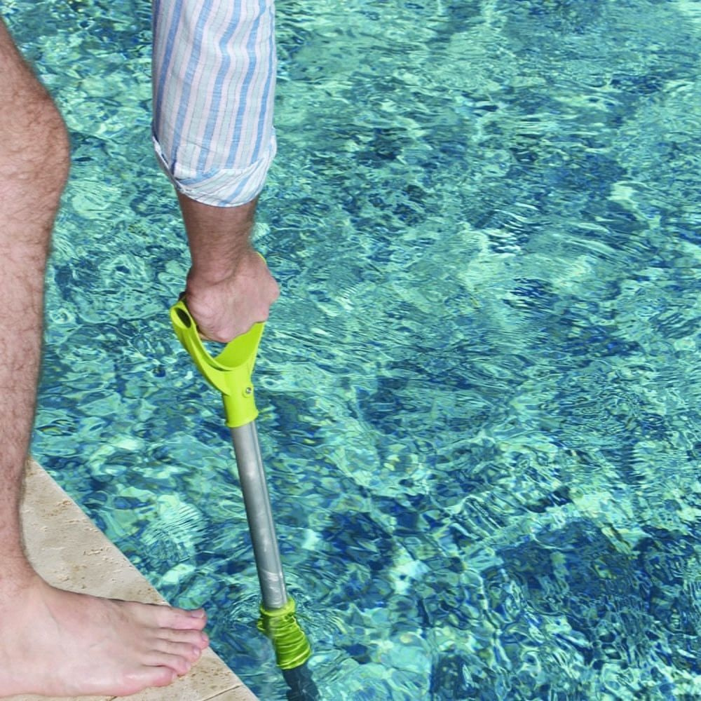 En man städar en pool med teleskopstången 