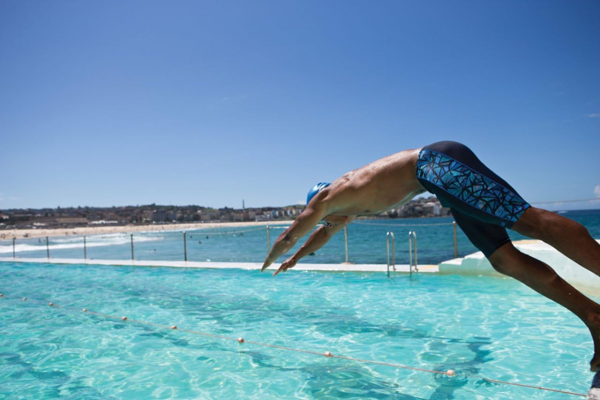 En man i badbyxorna dyker i en utomhuspool