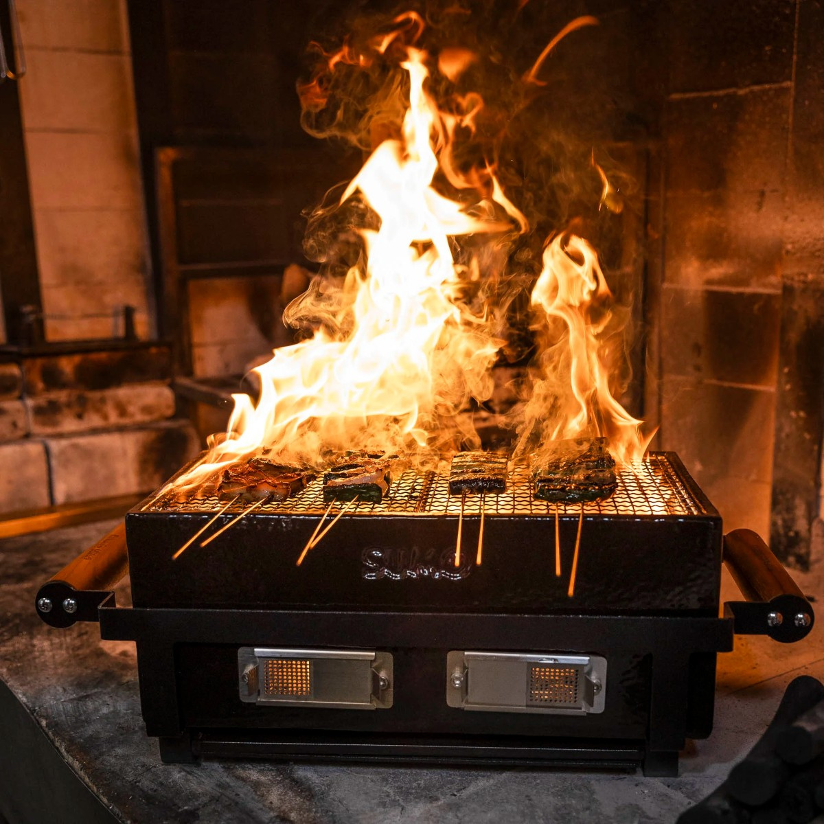 Bordsgrillen brinnande med kött på