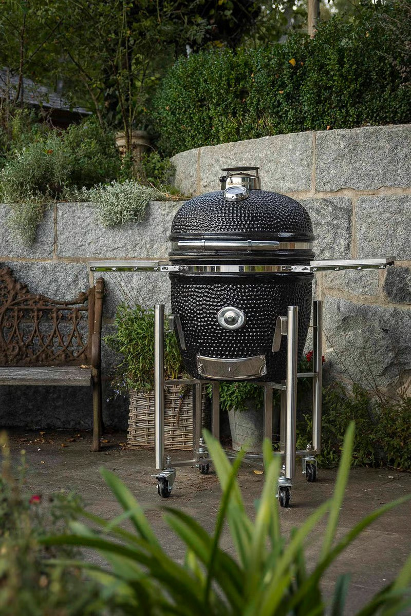 Grillen står ute framför en stenmur bredvid en blomkruka och en soffa