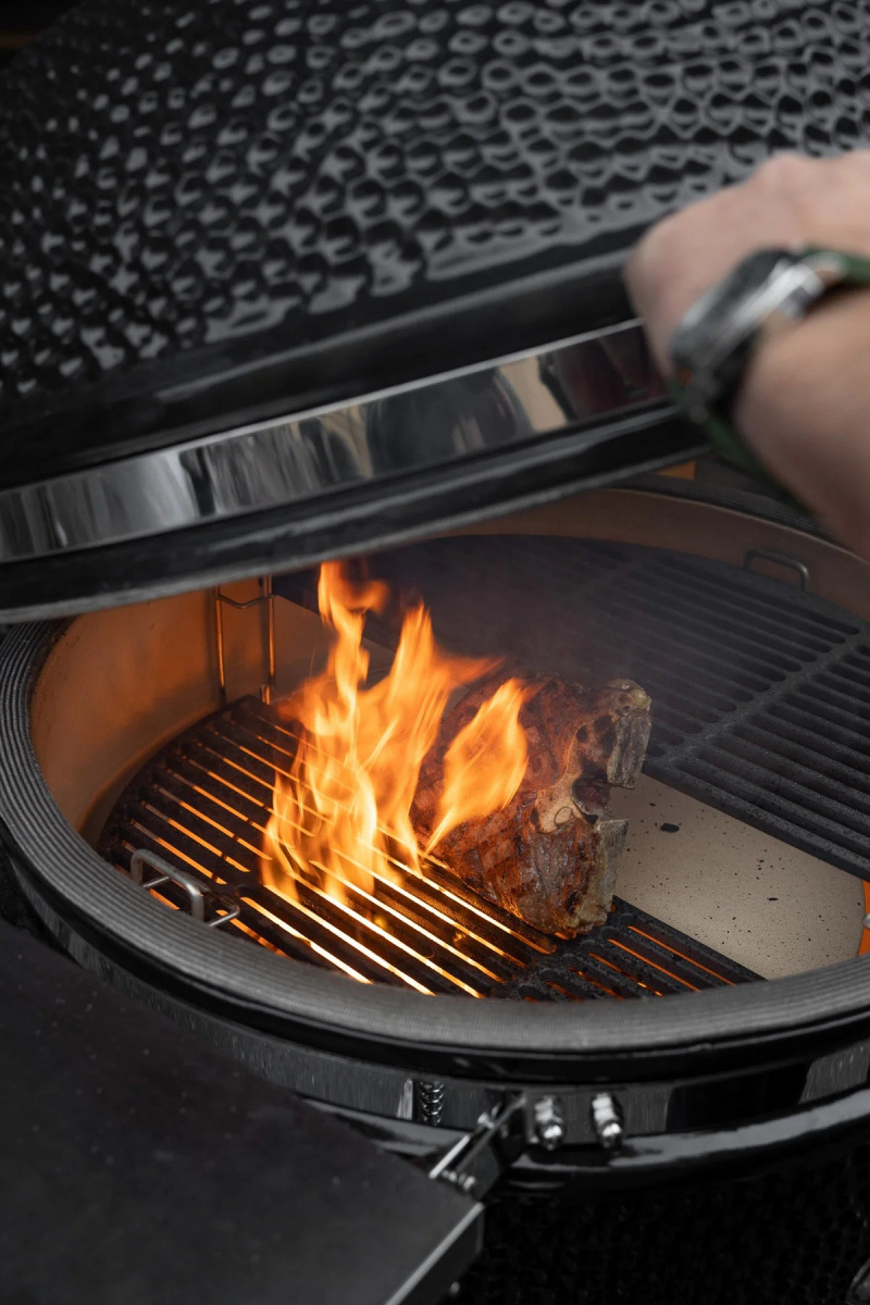 Närbild på en brinnande grill med locket halvöppet