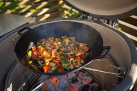 Wokpannan ingår ej Närbild på grillen med en wokpanna på gallret över glödande kol