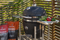 Borttagbara sidobord med krokar Grillen utomhus med grönsaker på sidobordet och kolsäckar bredvid