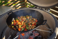 Wokpannan ingår ej Närbild på grillen med en wokpanna på gallret över glödande kol