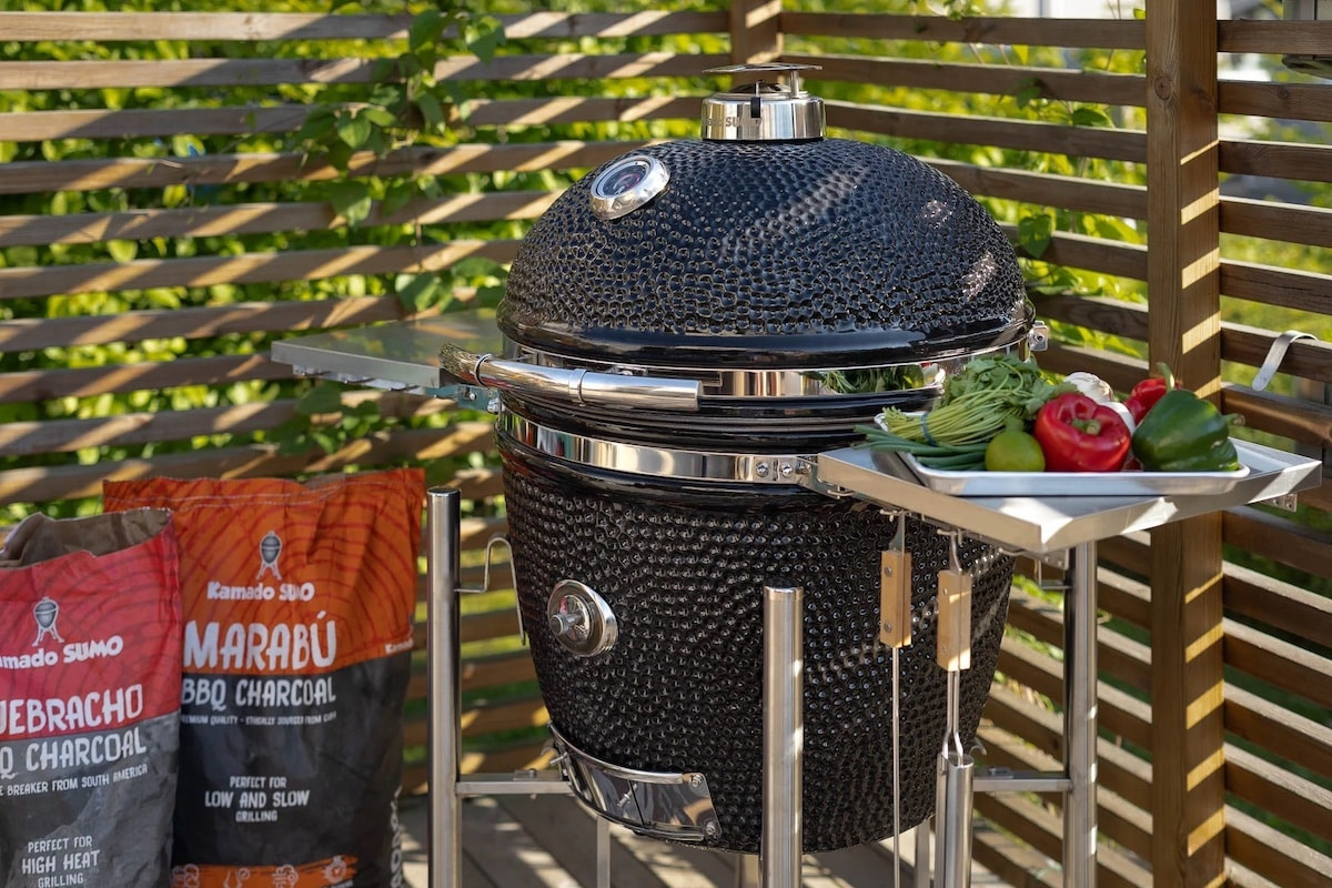 Grillen utomhus med grönsaker på sidobordet och kolsäckar bredvid