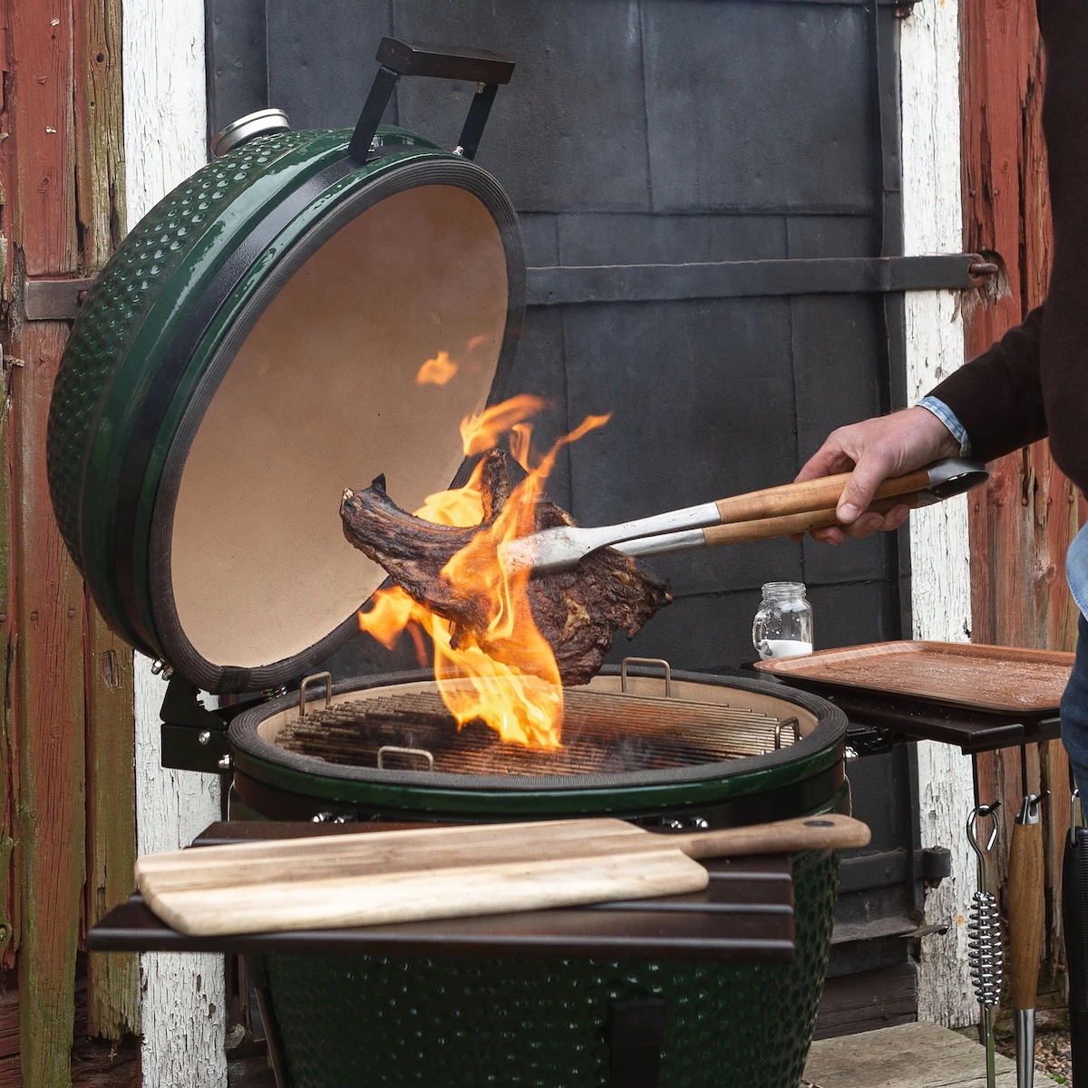 Grilltången används för att lyfta en köttbit över en brinnande grill