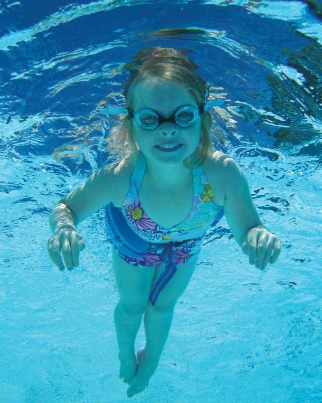 En flicka med guppy glasögonen simmar under vatten