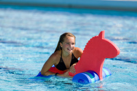 Flytleksak Stallion En tjej hänger på flytleksaken i en pool