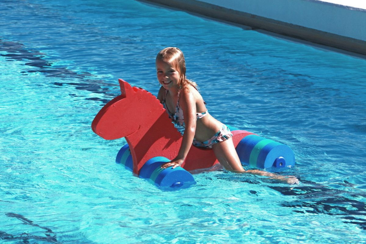 En tjej hänger på flytleksaken i en pool