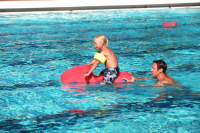 Flytleksak Bonda Ett barn sitter på flytleksaken medan en man puttar den