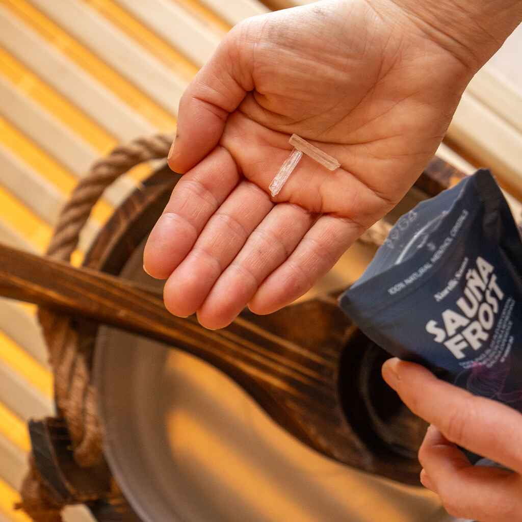 En hand håller två bastukristaller ovanför en bastusteva