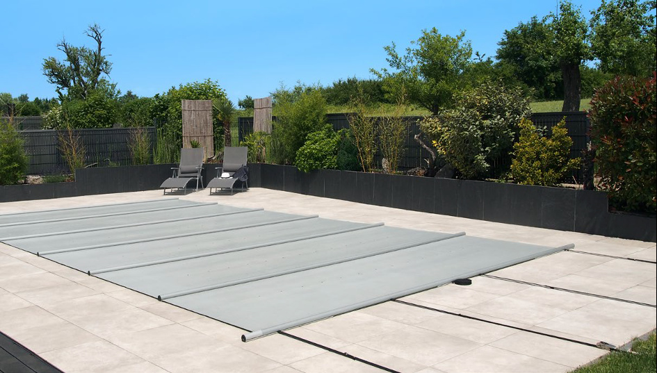 Poolskyddet i ljusgrått helt utrullat över en pool