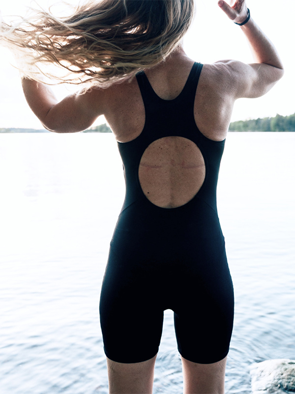 En dam i baddräkten sedd bakifrån utomhus vid en sjö