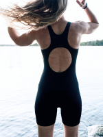 En dam i baddräkten sedd bakifrån utomhus vid en sjö