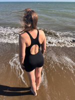 En dam i baddräkten sedd bakifrån utomhus vid havet