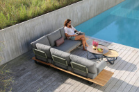 Loungesoffan kombinerad med andra delar av Natural serien En kvinna läser på soffan vid en pool