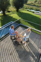 STAY Compact Bord & 2 Pallar, Mörkgrå Aluminium Två personer sitter utomhus på pallarna med bordet mellan dem