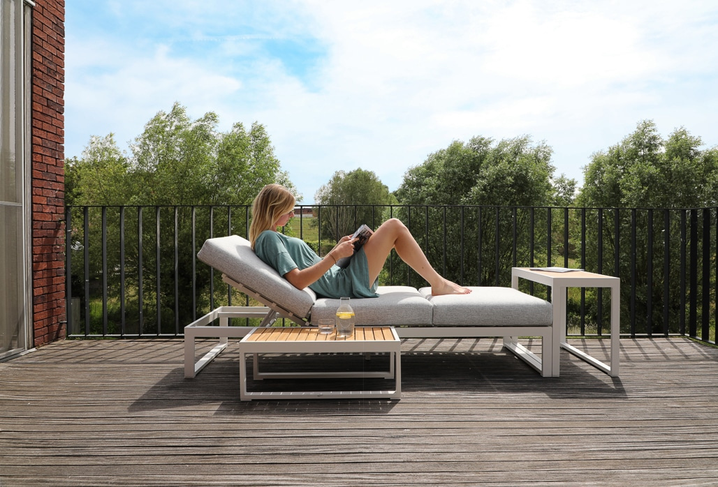 En dam sitter på soffan ute på ett trädäck