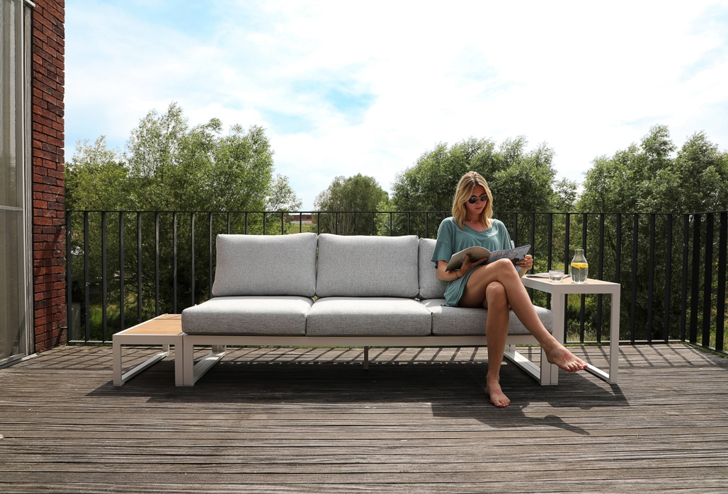 En dam sitter på soffan ute på ett trädäck