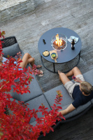Bild visar bordet i svart Fogo bordet bredvid en soffa med två personer sittande i den