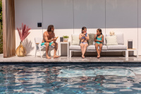 Bilder visar soffan med ljust tyg & vit ram Två flickor sitter på soffan och en man i en fåtölj vid en pool