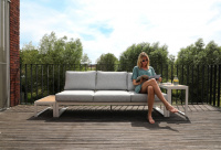 Sidoborden ingår ej En dam sitter på soffan ute på ett trädäck