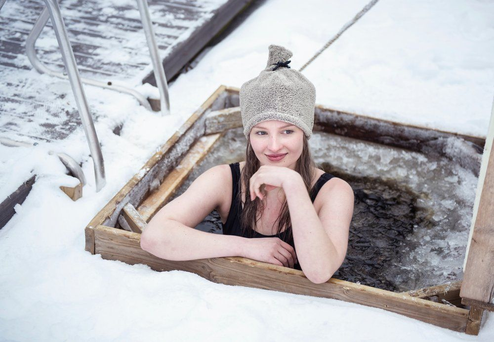 En tjej har mössan på sig när hon badar i en isvak 