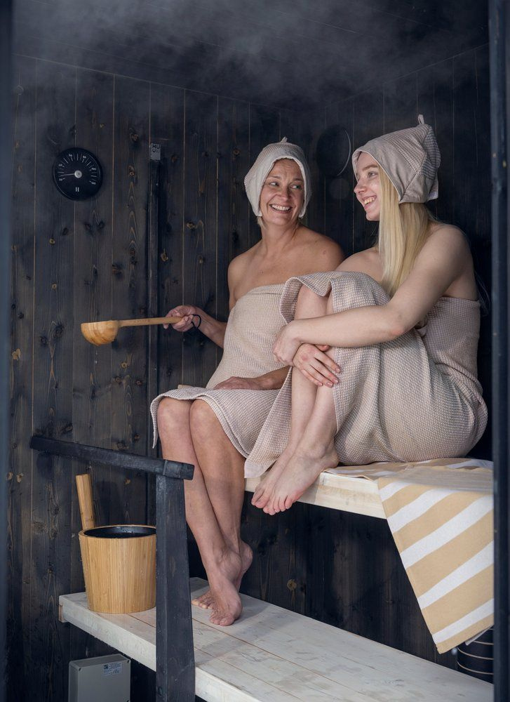 Bastuhinken står på bänken i bastun nedanför två damer